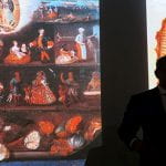 A wide shot of students in a classroom identifying works of art during a visual quiz.